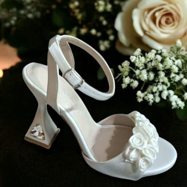 Ivory bridal heel with geometric crystal-embellished block heel, floral appliqué on front strap, and ankle buckle strap – displayed on a dark background. Beirut Lebanon