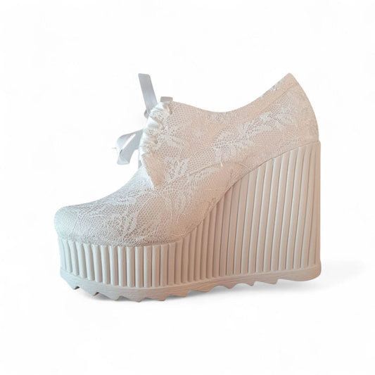 Beige wedge shoe with lace detailing on a white background
