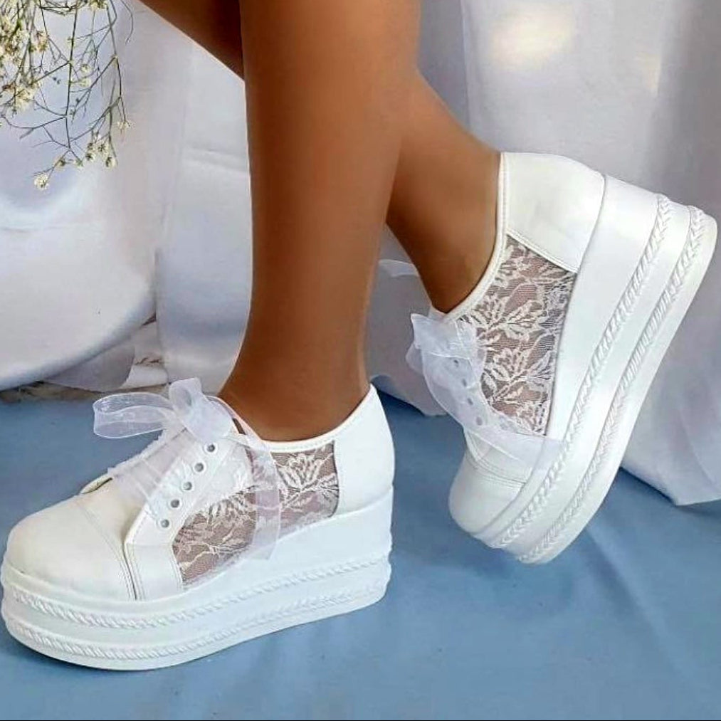 White sneakers with lace details on a light blue background