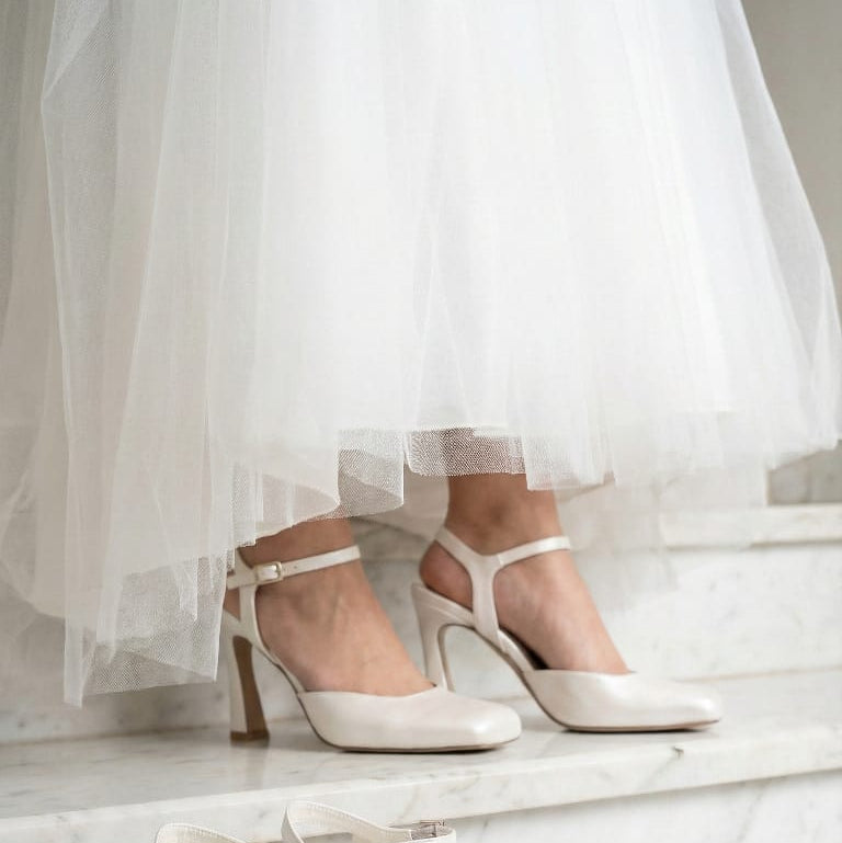 Pair of Pearl white high-heeled shoes on a marble surface with a light background