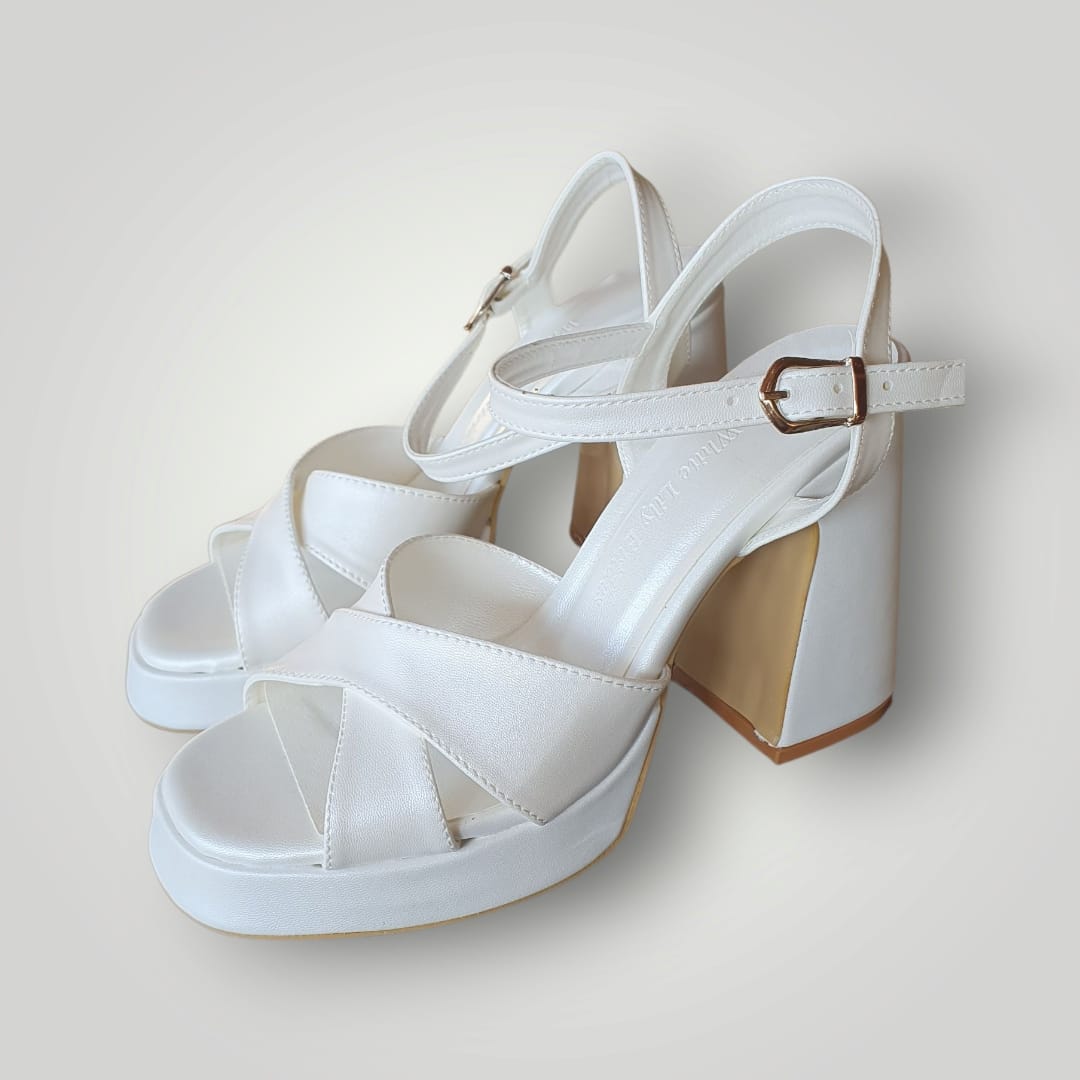 White block heel sandals with leather crisscross straps, ankle buckle closure, and platform sole