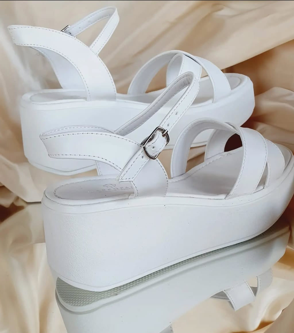 White leather platform sandals with 7 cm heel, featuring adjustable straps, displayed on a mirror with silky fabric background. Beirut Lebanon