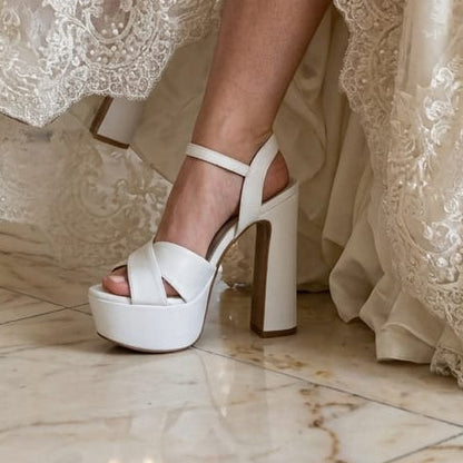 white platform high-heel sandals in a grand interior with marble floors and arches.