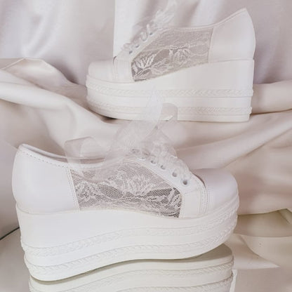 White high-heeled shoes with lace details on a light background