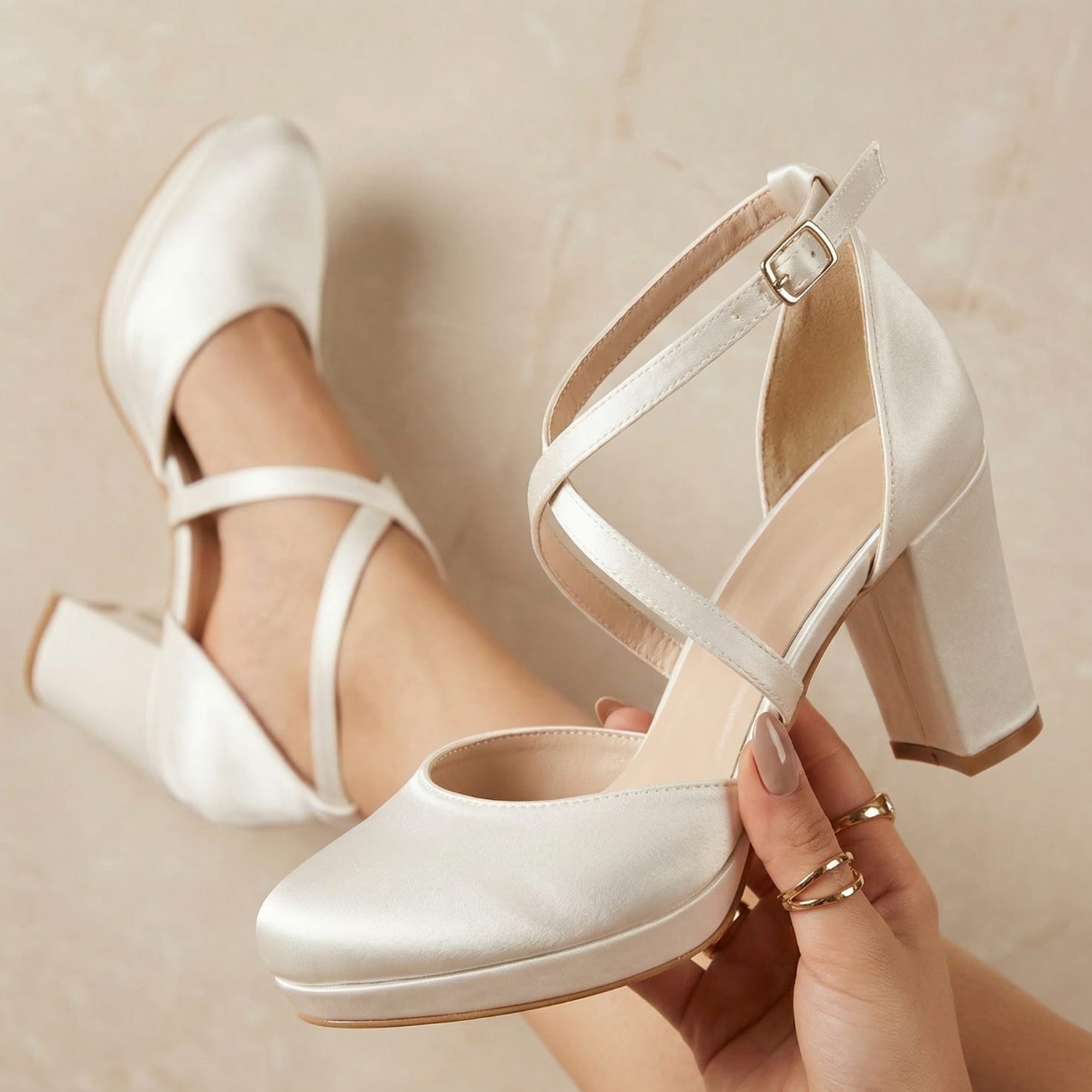 8cm pearl White heeled shoes being held against a neutral background