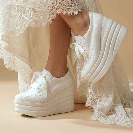 White lace-up platform sneakers worn with a white lace dress, shown on a model against a warm beige background.