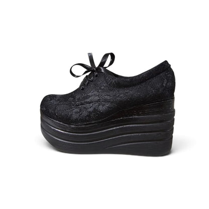 A single black lace-up platform shoe with a textured, jacquard-like fabric upper, shown from a side profile view against a plain white background.
