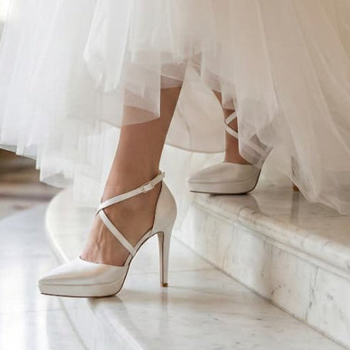 Bride wearing a white wedding dress and wedding shoes on marble steps.