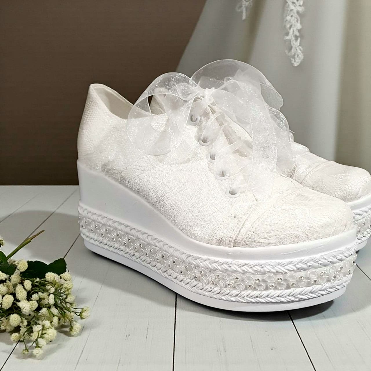White platform sneakers Rock with decorative elements on a wooden floor.k