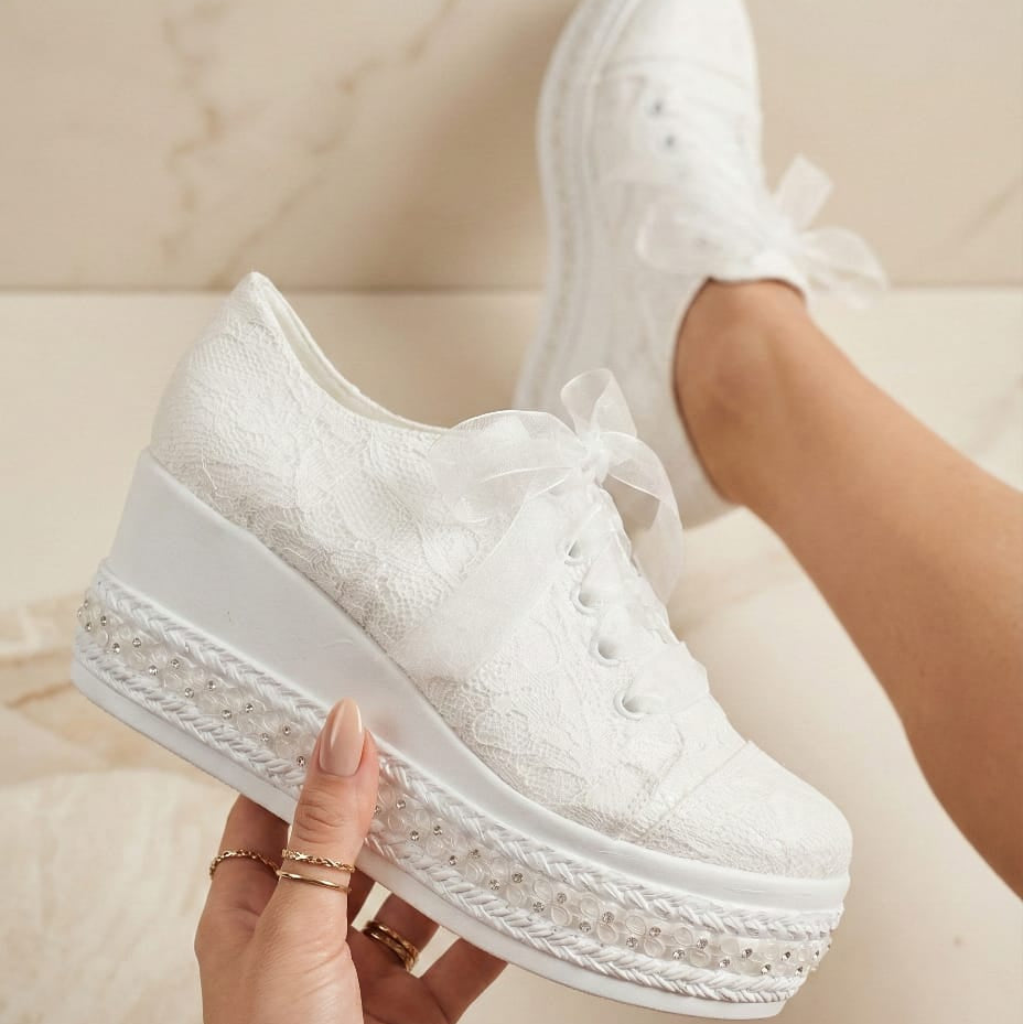 Bridal White sneakers with platform sole held by a hand against a neutral background