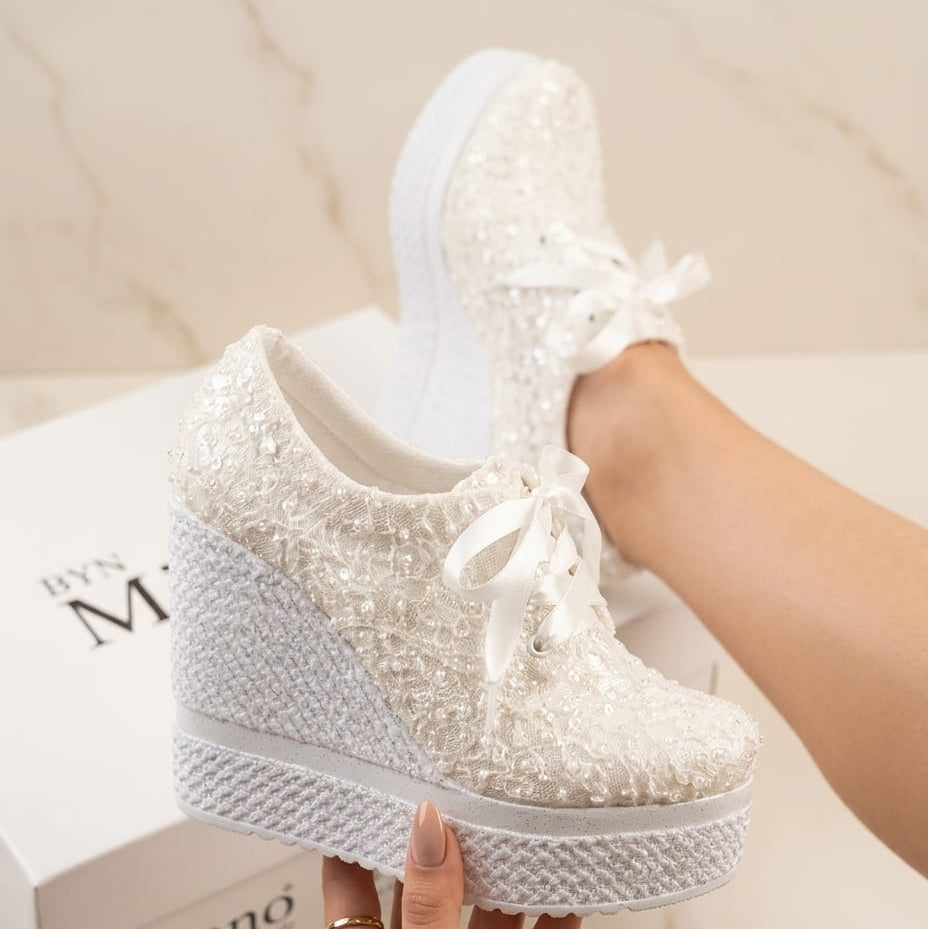Off-White sneakers with lace-up design held by a hand on a light background