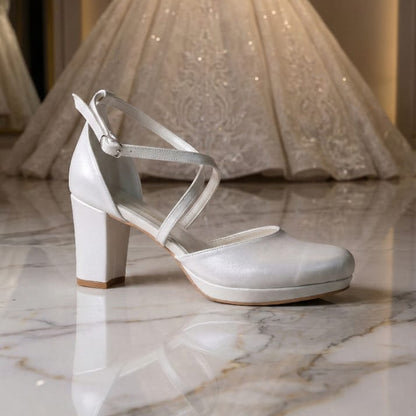 Pearl White wedding shoe with a wedding dress in the background on a marble floor Beirut