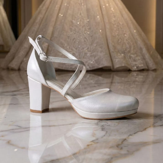 Pearl White wedding shoe with a wedding dress in the background on a marble floor Beirut