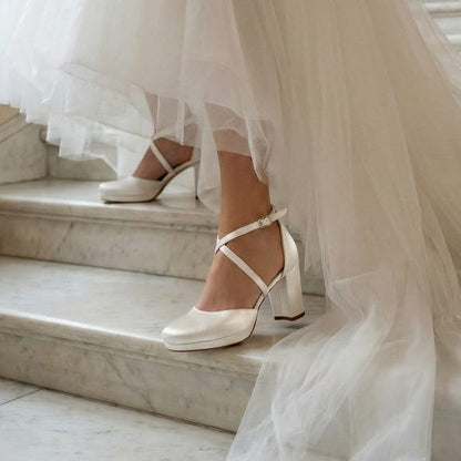 Bride wearing White Lily Brides white block heel wedding shoes with crisscross straps walking down marble stairs in a voluminous tulle gown. in Beirut Lobby