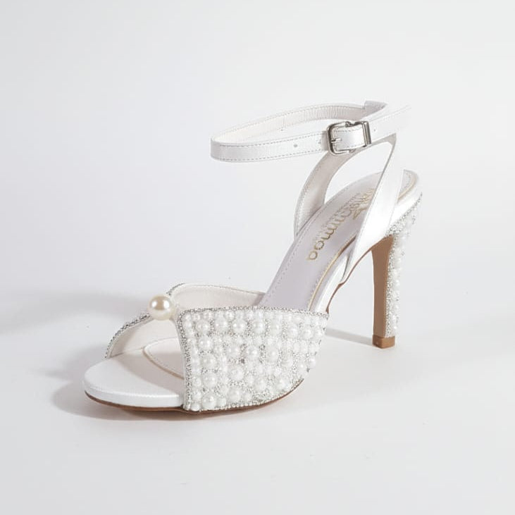 Round-toe bridal stilettos with hand-applied pearls and adjustable ankle strap for wedding day elegance.