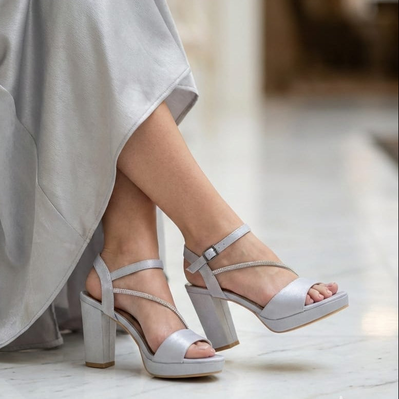 Silver satin sandals worn by a person sitting on a chair with a blurred background in Beirut Lebanon