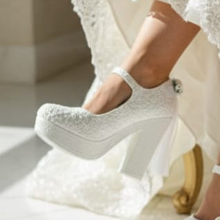 White wedding dress with matching shoes on a marble surface