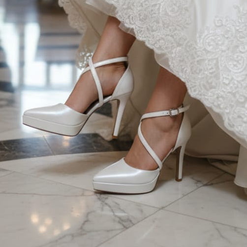 White wedding shoes worn with a lace wedding dress in an elegant indoor setting.