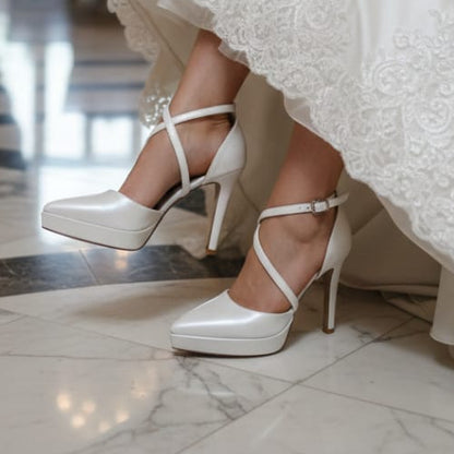 White wedding shoes worn with a lace wedding dress in an elegant indoor setting.