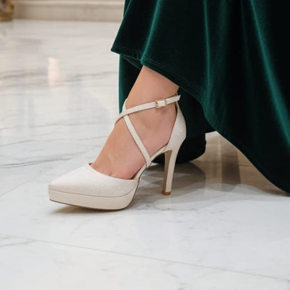 Person wearing a green dress and white high-heeled shoes in an elegant interior setting.