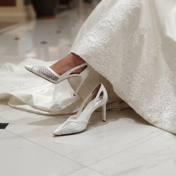 White wedding shoes worn with a white dress in an indoor setting.