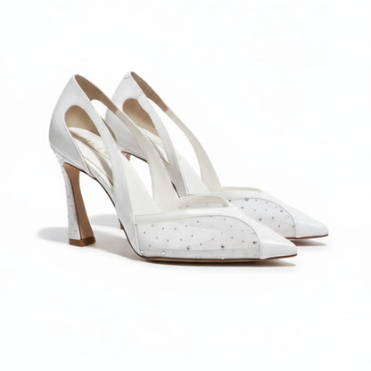 White high-heeled shoes with studded details on a white background