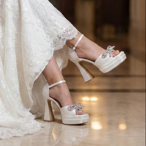 Person wearing a white lace dress and high-heeled shoes in an elegant indoor setting.