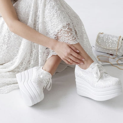 Person wearing white lace dress and platform shoes on a white background