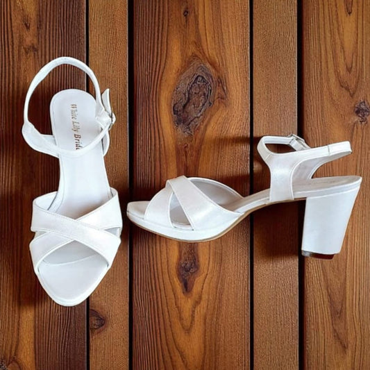 White high-heeled sandals on a wooden surface