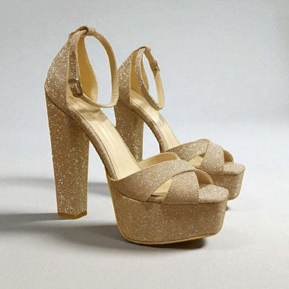 Gold glitter high-heeled shoes on a light gray background