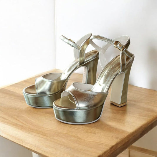 Gold high-heeled shoes on a wooden surface with a white background