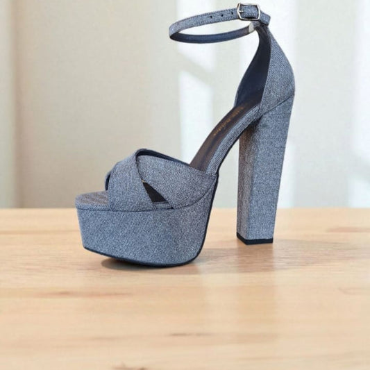 Blue denim platform sandal on a wooden surface with a neutral background