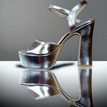 Silver high-heeled shoe on a reflective surface with a gray background
