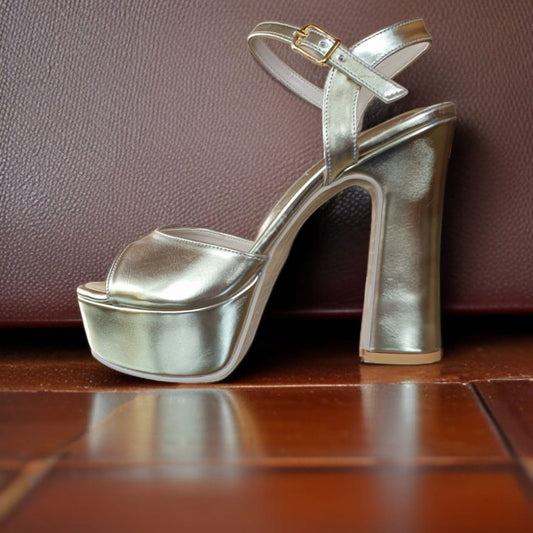 Gold high-heeled platform shoe on a wooden surface with a brown leather background