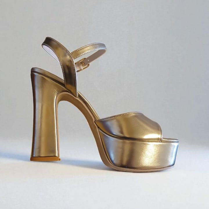 Gold high-heeled shoe on a light gray background