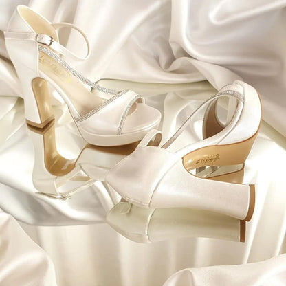 Pair of white high-heeled shoes on a soft white fabric background