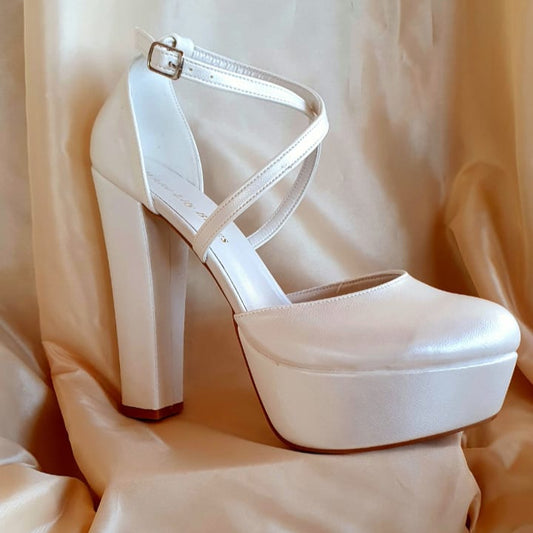 White high-heeled platform shoe on a beige fabric background