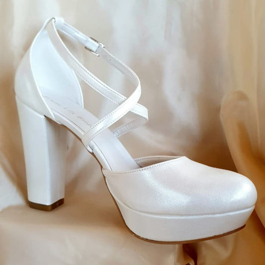 White high-heeled shoe on a beige fabric background