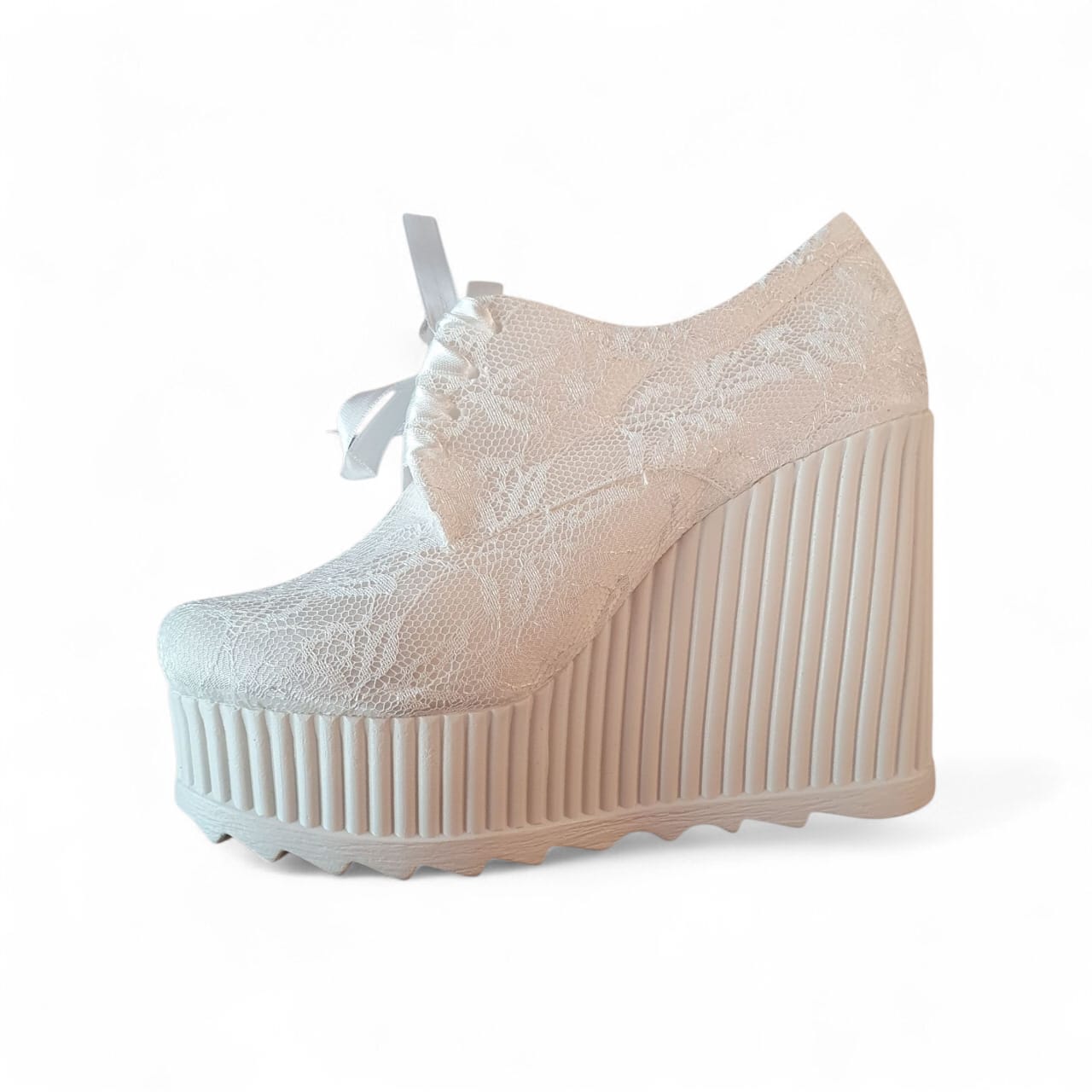 Beige wedge shoe with lace detailing on a white background