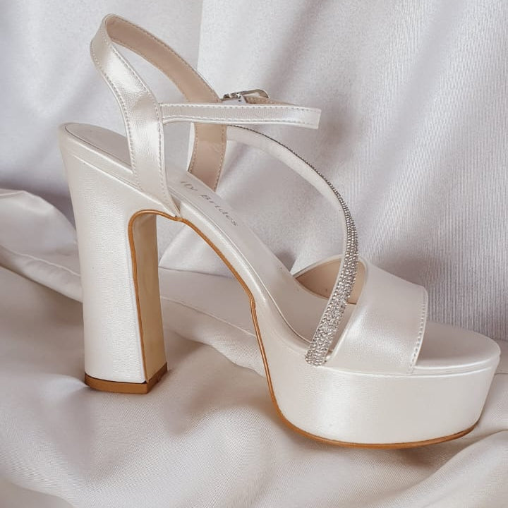 White high-heeled shoes with a platform on a white fabric background