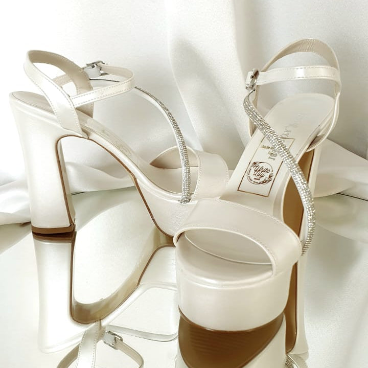 White high-heeled sandals with a brand logo on a white background