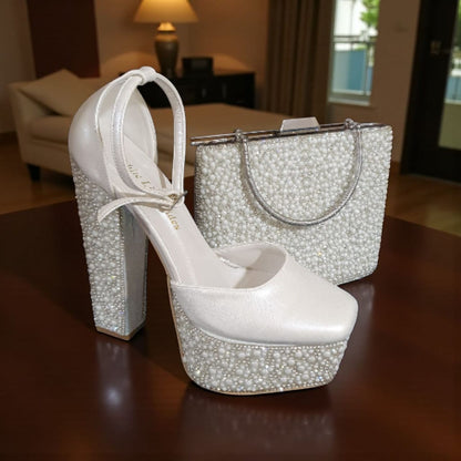 White high-heeled shoe and matching handbag with rhinestone details on a wooden surface.