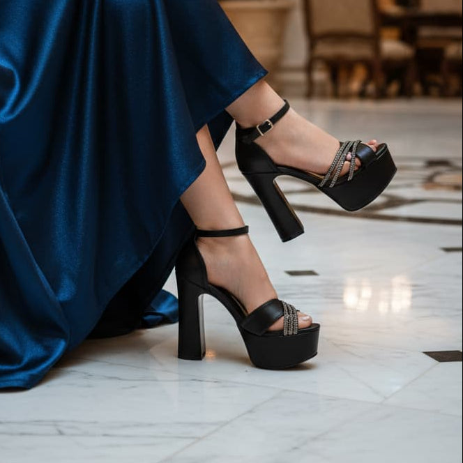 Person wearing a blue dress and black high-heeled shoes in an elegant indoor setting.