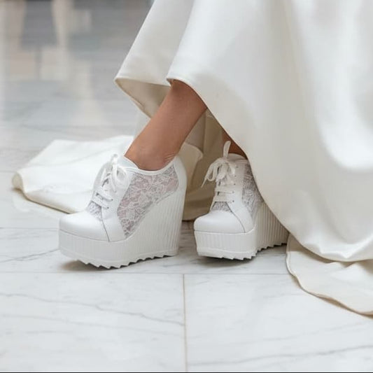 Person wearing a white dress with white platform shoes in an indoor setting.