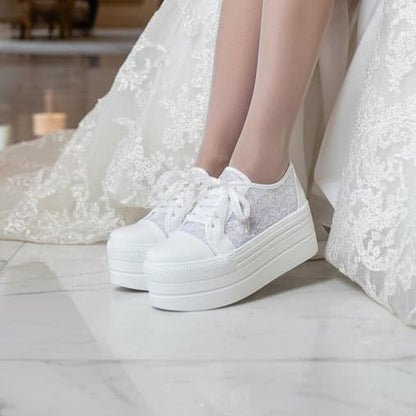 White sneakers worn with a white lace dress on a light background