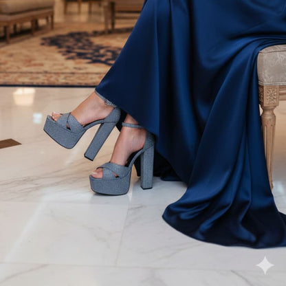 Woman in a navy blue gown sitting on a chair in an elegant interior setting.