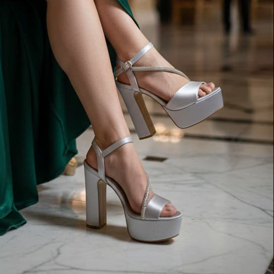 Person wearing a green dress and silver high heels in an elegant indoor setting.