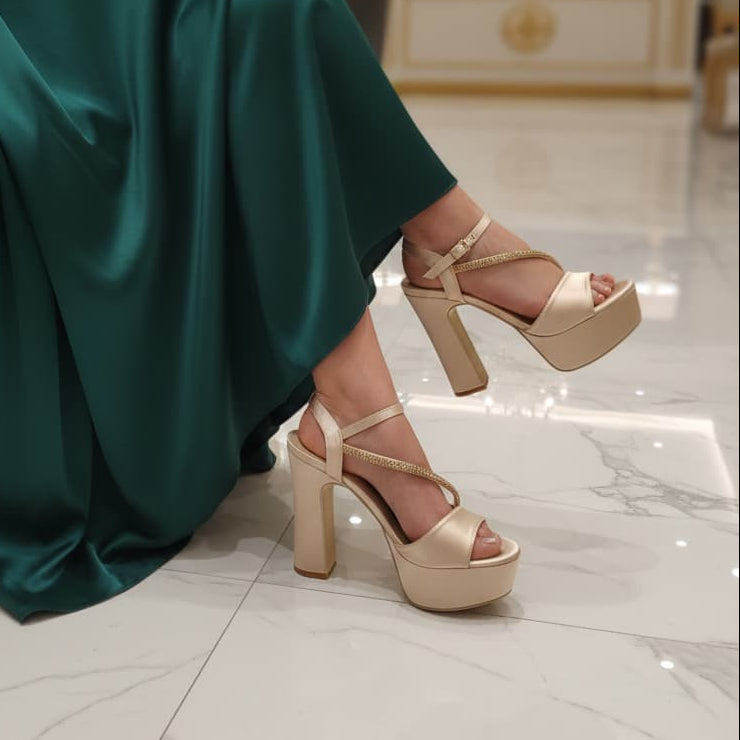 Person wearing a green dress and beige high-heeled sandals in an indoor setting.