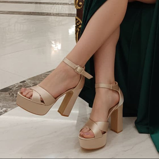 Beige high-heeled platform  Tan Sandal shoes worn with a green dress on a marble floor.