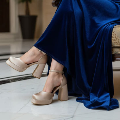 Gold high-heeled shoes and a blue dress in an indoor setting.